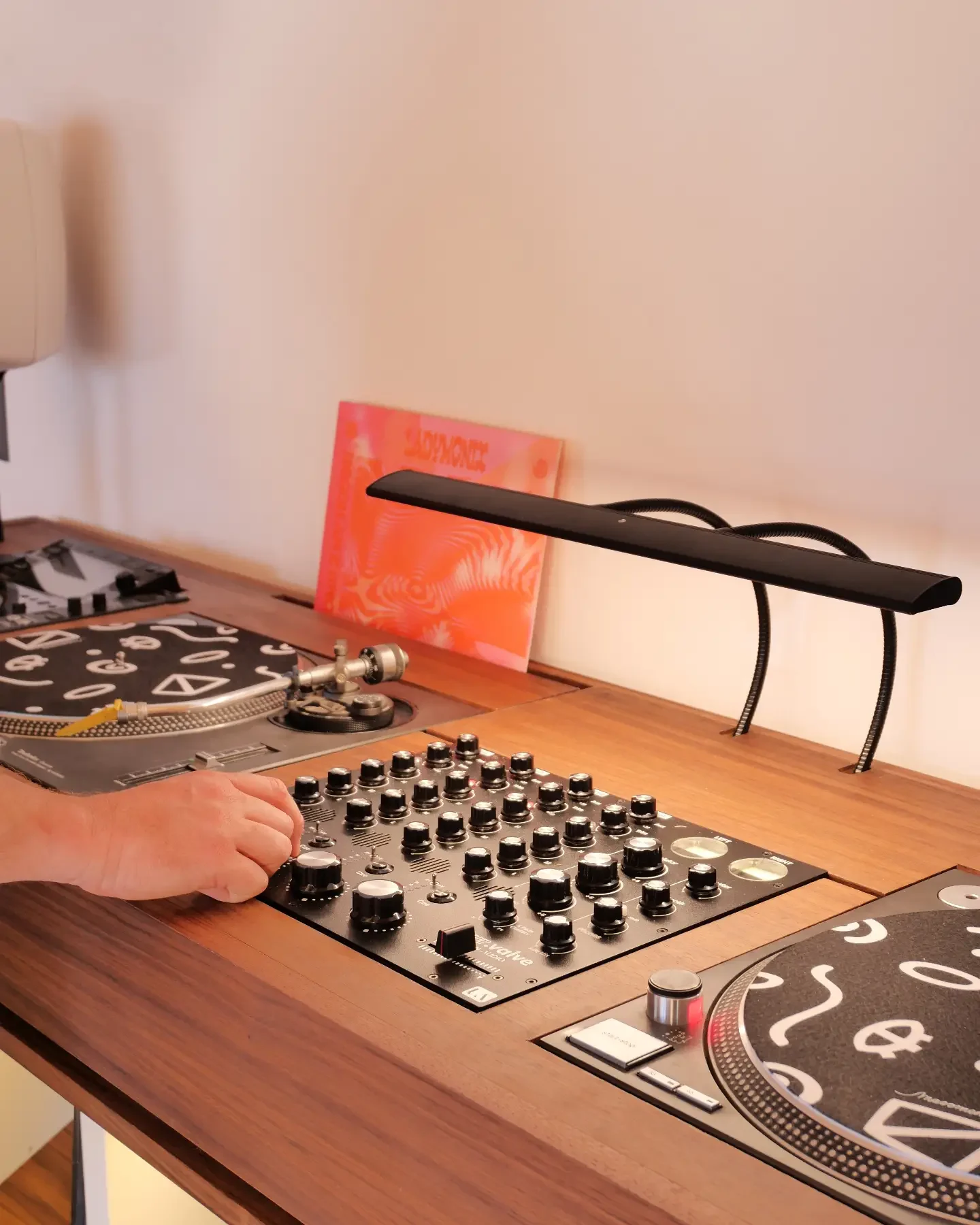 Main sur une table de mixage rotative encastrée dans un plateau en noyer