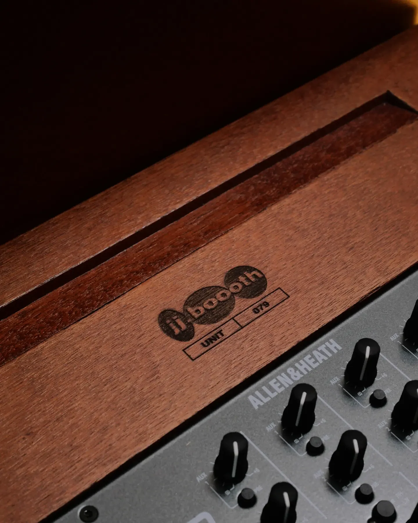 Logo jj.boooth gravé dans le bois à côté d’une table Allen & Heath