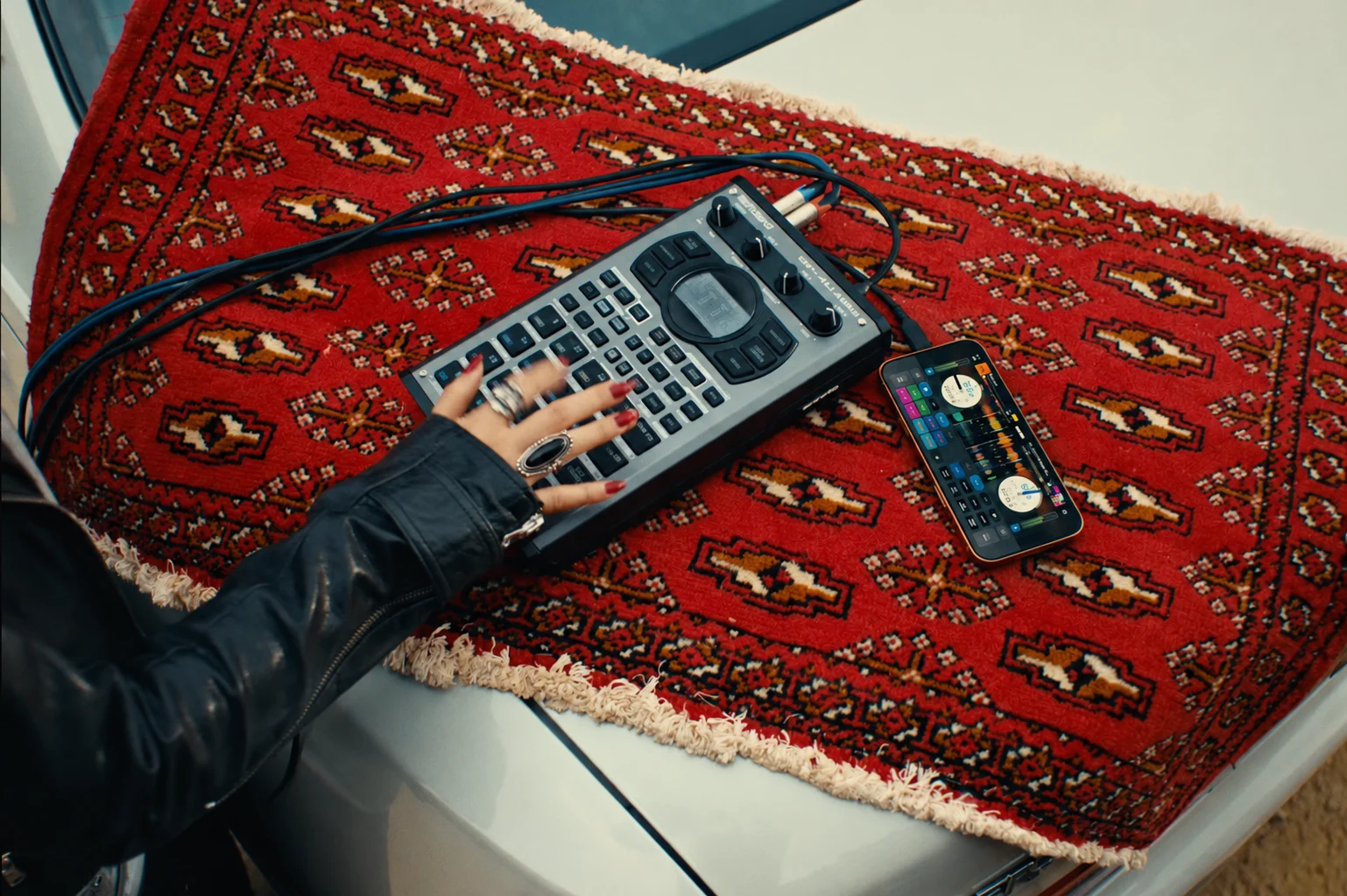 Un iPhone affichant Serato DJ, branché à un sampler Roland SP-404MKII sur un tapis rouge