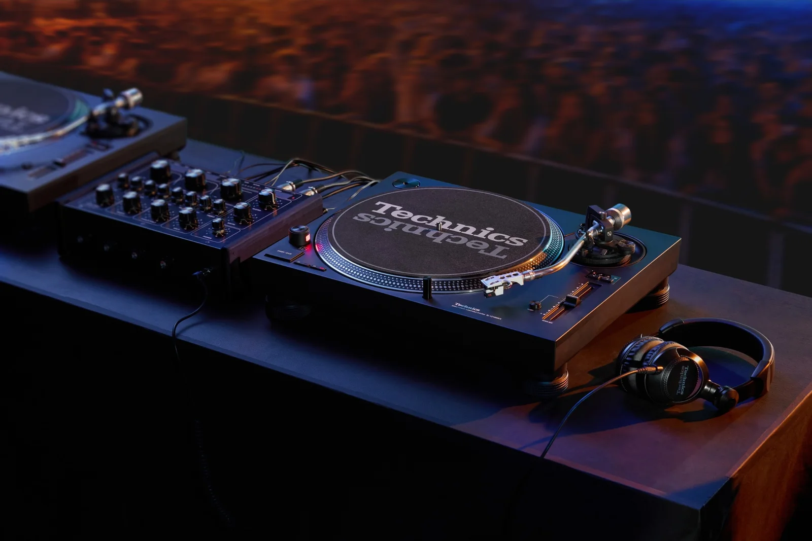 La platine Technics SL-1210MKX dans une cabine DJ, à côté d’une table de mixage, face à la foule